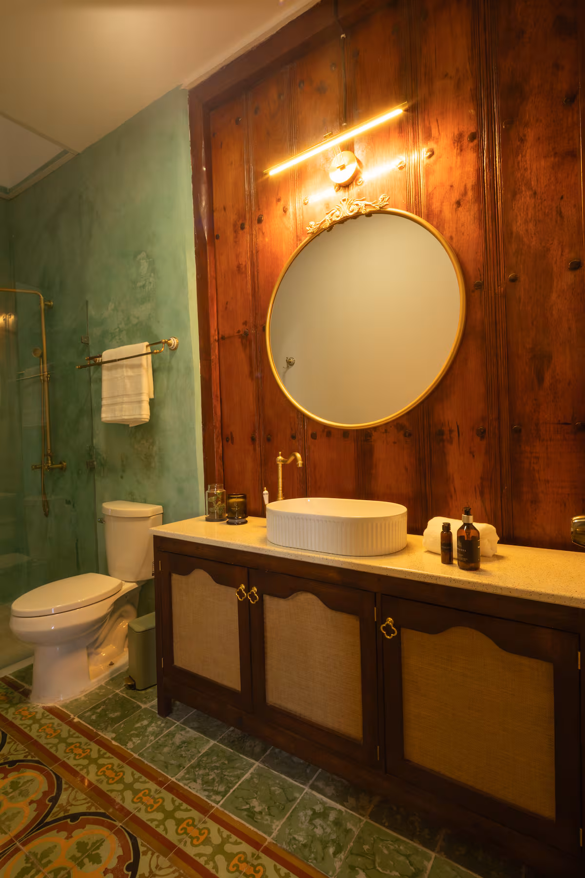 Baño con detalles de madera, mosaico y espejo circular