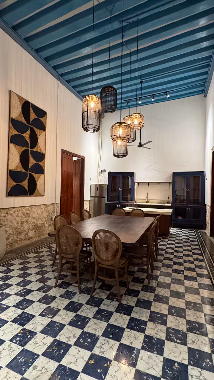 Comedor compartido con mesa larga y lámparas de mimbre